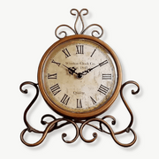 Antique-style bronze iron tabletop clock on a wooden desk