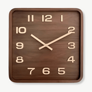 Square solid wood wall clock with silent quartz movement on a white wall