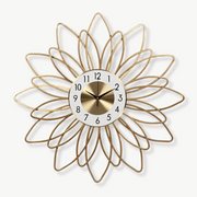 Golden flower metal wall clock with analog hands on a white wall