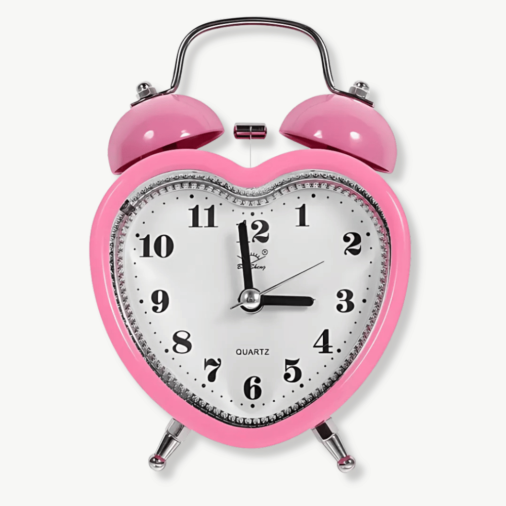 Pink heart-shaped alarm clock with double bell on white background