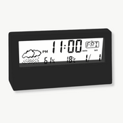 Black LCD weather alarm clock showing time temperature and humidity on nightstand