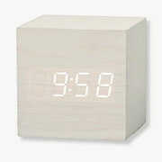 Square LED alarm clock with dark wood frame on a bedside table