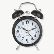 Retro quartz double bell alarm clock in black metal on a bedside table