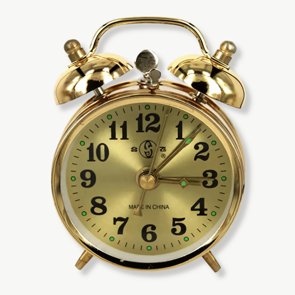 Gold vintage mechanical alarm clock on a wooden nightstand