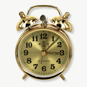 Gold vintage mechanical alarm clock on a wooden nightstand