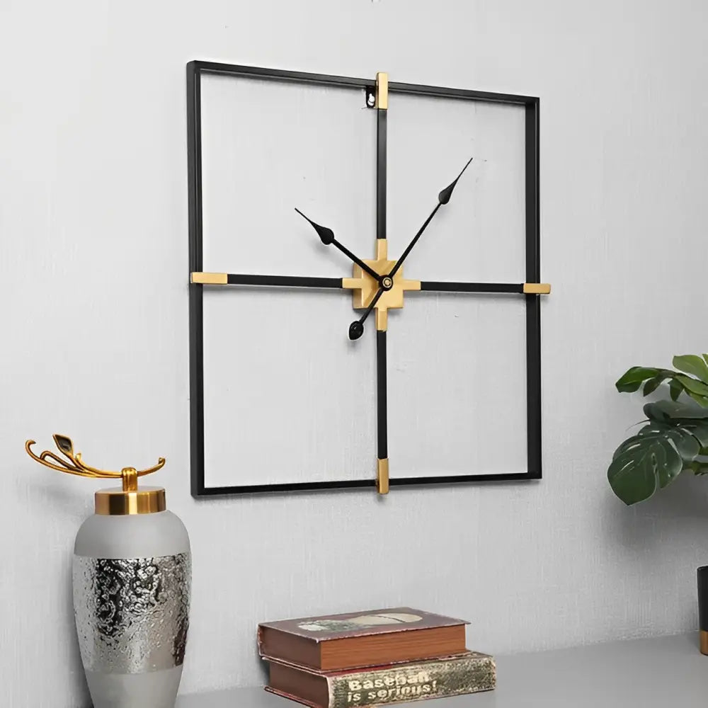 close-up of black metal frame and gold-tone hands on square wall clock